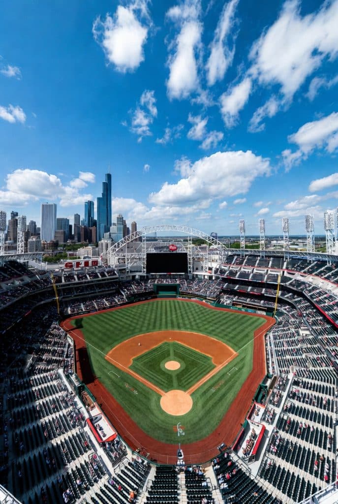 Orioles vs White Sox Beautiful wide aerial view of Guaranteed Rate Field in Chicago on a sunny day, full baseball stadium with green grass diamond, packed stands, Chicago skyline in background, professional sports photography, vibrant colors, high resolution