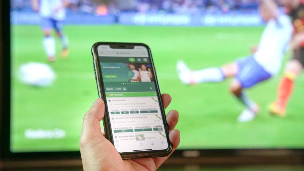 A person using a mobile device to access a sports betting site, illustrating the focus of Bill A4003 on New Jersey sports betting responsible gaming mechanisms
