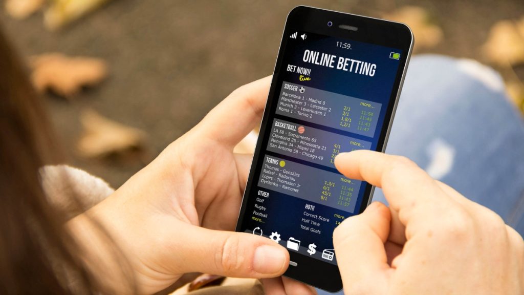 A close-up of a person using a mobile sports betting app to place wagers on soccer and basketball, a primary focus of modern legislation like an Ohio Sports Betting Bill.