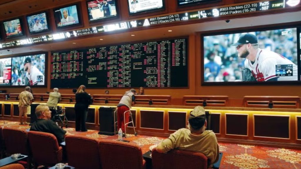 A retail sportsbook with patrons watching various sports on large monitors, used to explain the proposed tax surcharge on New Jersey sports betting for World Cup wagers.