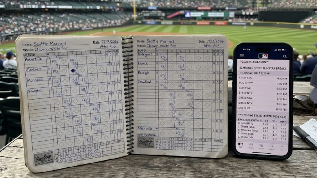 A baseball scorecard notebook open to a Seattle Mariners versus Chicago White Sox game alongside a smartphone displaying pitching stats and a schedule. This hands-on tracking setup represents a disciplined approach to developing the Best MLB Betting Strategy after the All-Star Break.